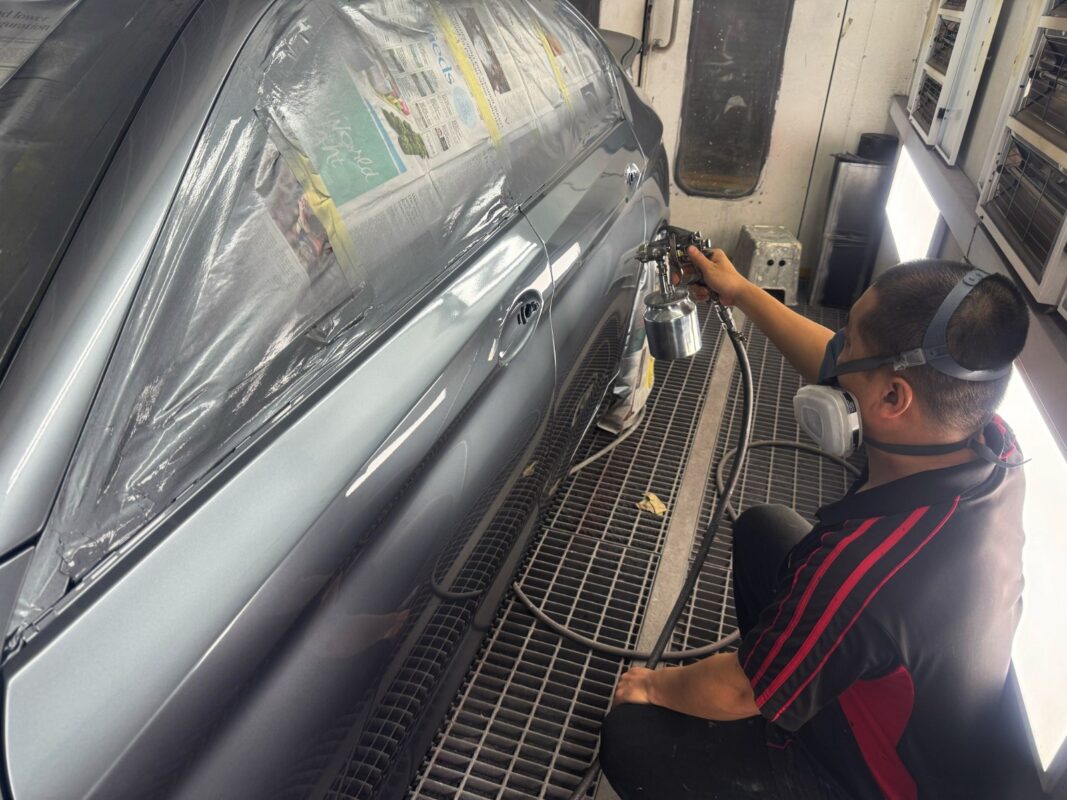 A Revol Carz painter applying the new coat to the BMW 5 Series in the spray booth.