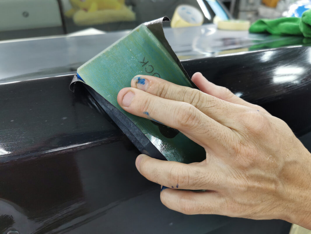 Wet-sanding a panel on the BMW 5 Series to create a smooth foundation.