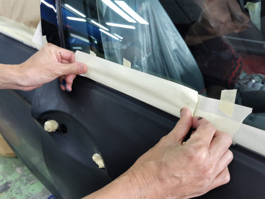 Masking non-painted surfaces on the BMW 5 Series ahead of the spray booth.