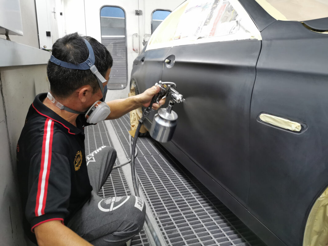 Spray painting underway on the BMW 5 Series inside the booth.