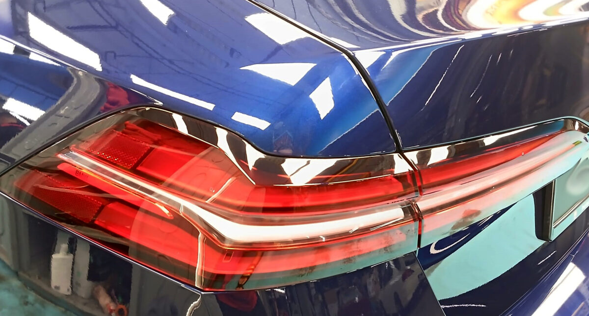 The coated bonnet of the BMW 5 Series under workshop lighting.