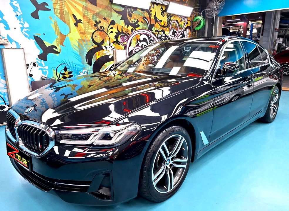 Black BMW 5 Series front three-quarter view in the Revol Carz workshop after ZeTough Ceramic coating.