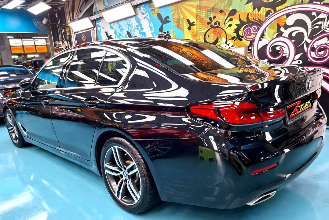 Rear three-quarter view of the black BMW 5 Series in the workshop.