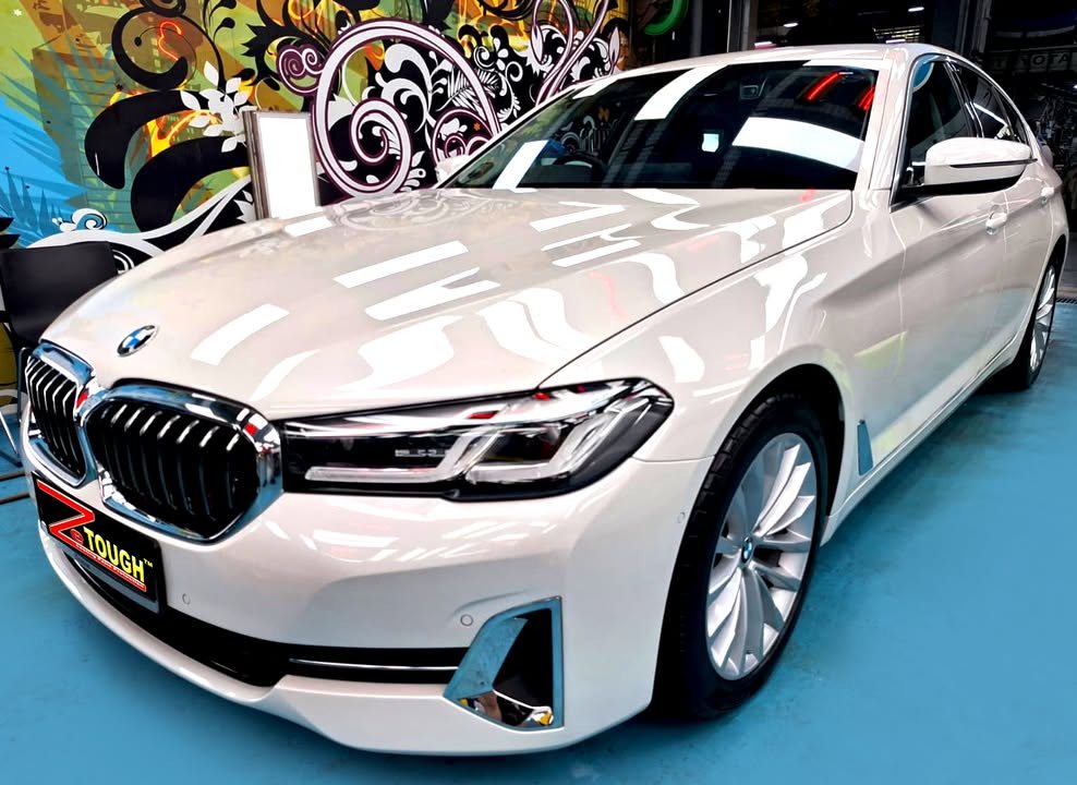 Front three-quarter view of a white BMW 5 Series in the Revol Carz hall after coating.