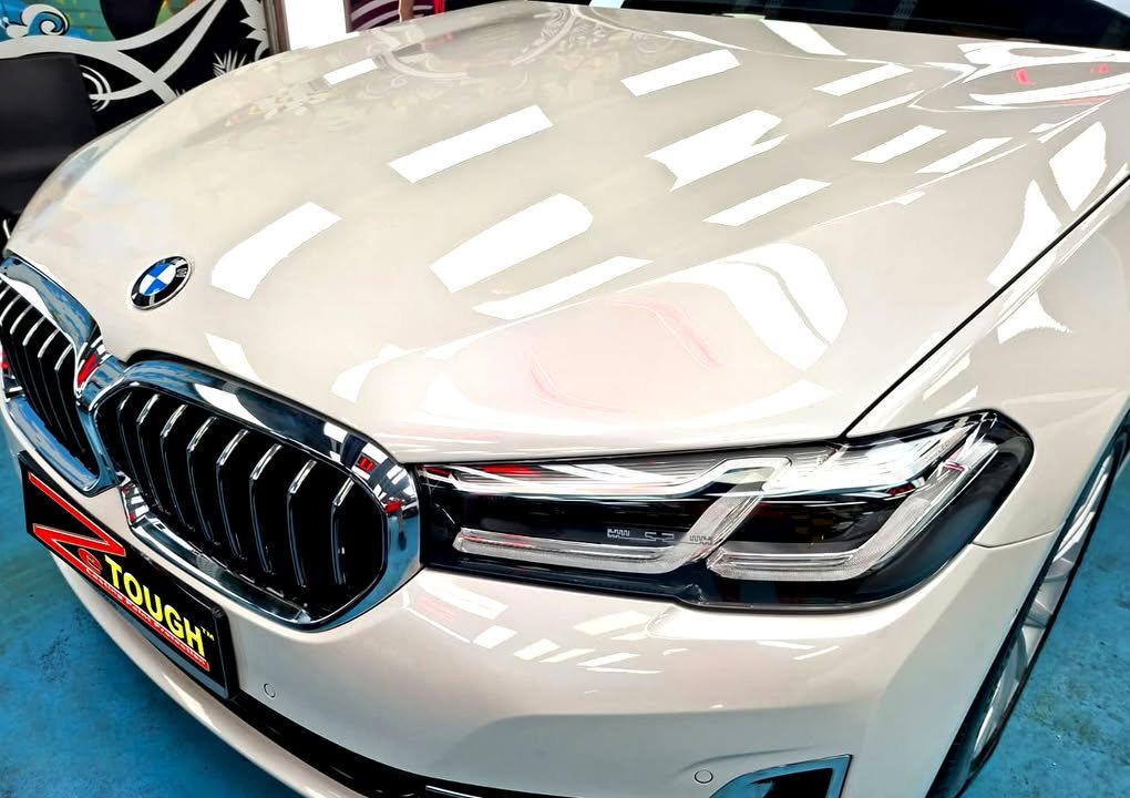 Bonnet, kidney grille and headlight of the white 5 Series with reflections.