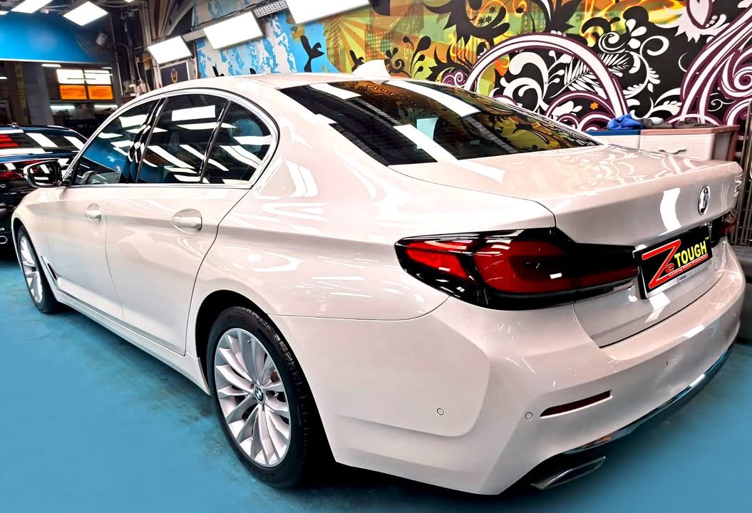 Rear three-quarter view of the white BMW 5 Series showing the tail lights.