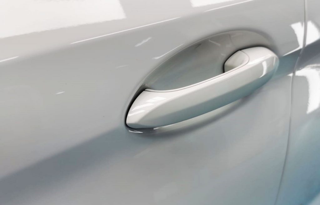 The coated bonnet of the BMW 502i under workshop lighting.