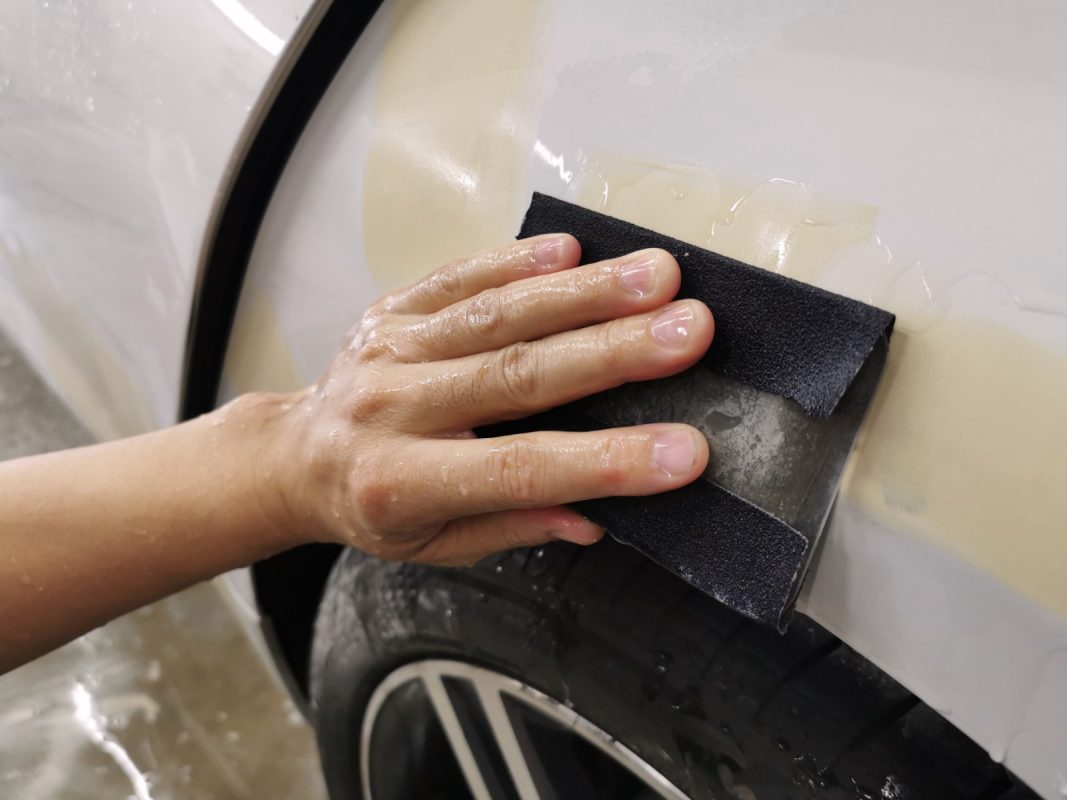 Wet-sanding the 520D's panels to smooth the existing paintwork.