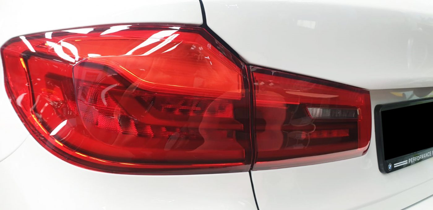 The coated bonnet of the BMW 520i under workshop lighting.