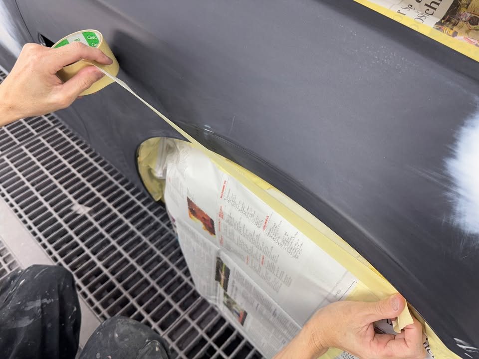 Taping paper over the wheel of the BMW inside the spray booth.