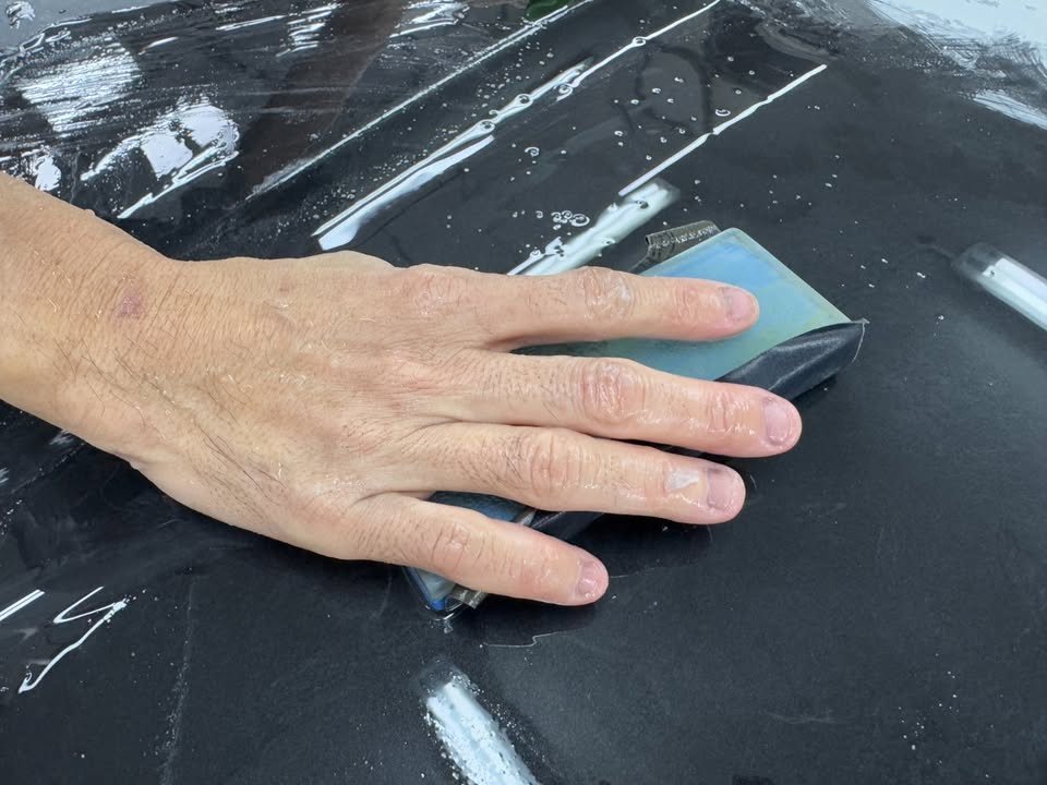 Wet sanding the freshly painted black panel of the BMW.
