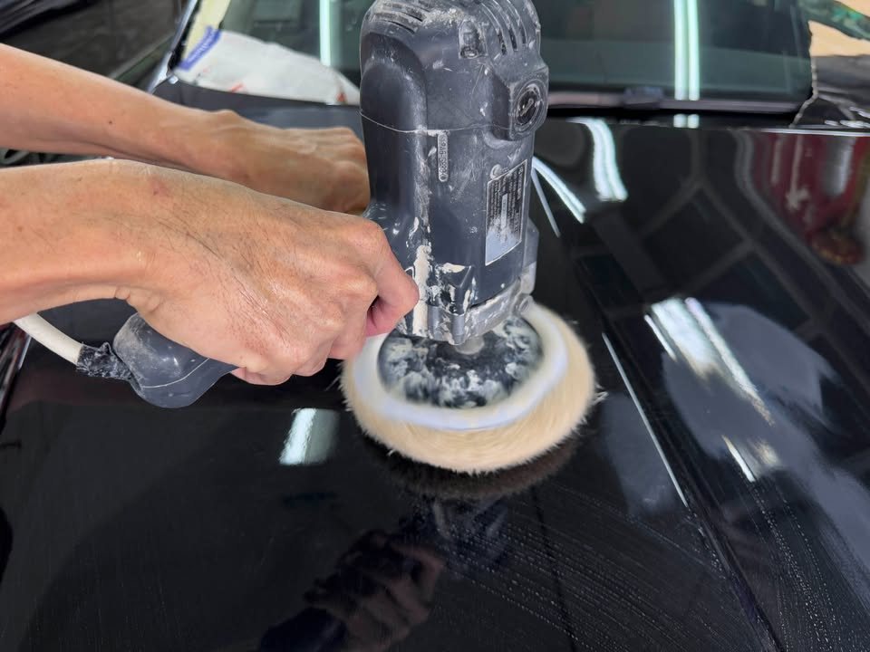 Rotary polisher with a wool pad working on the glossy black paint.