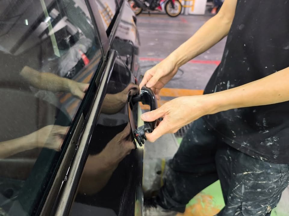 Technician refitting the door handle on the black BMW.