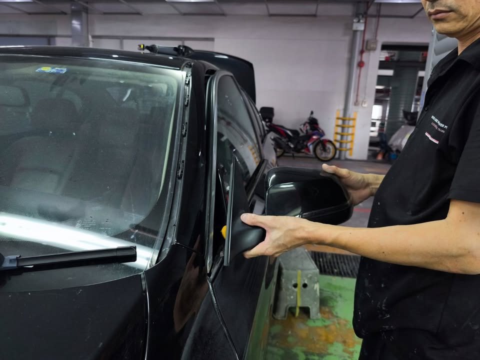 Technician fitting the side mirror back onto the black BMW.