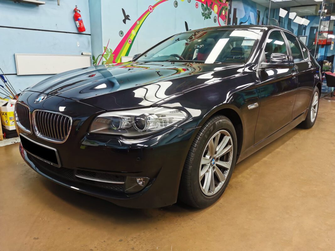 The BMW 520i as it arrived at Revol Carz, damage and scratches visible across the panels.