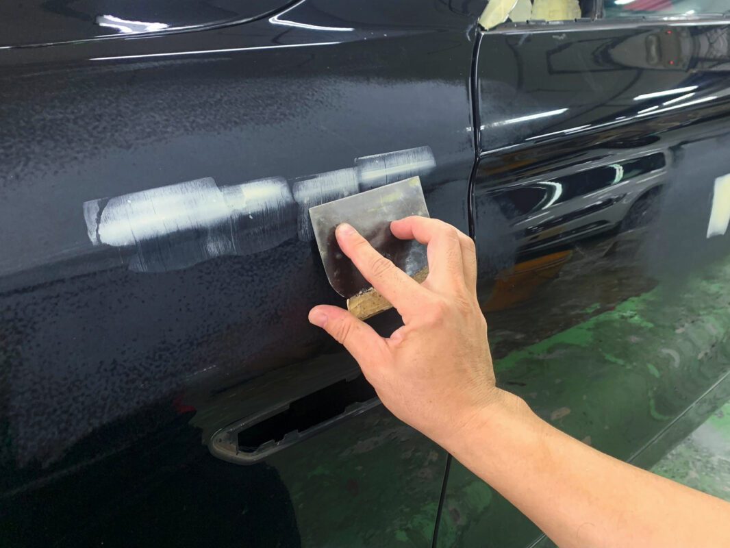Wet-sanding a panel on the BMW 520i to level the surface before priming.