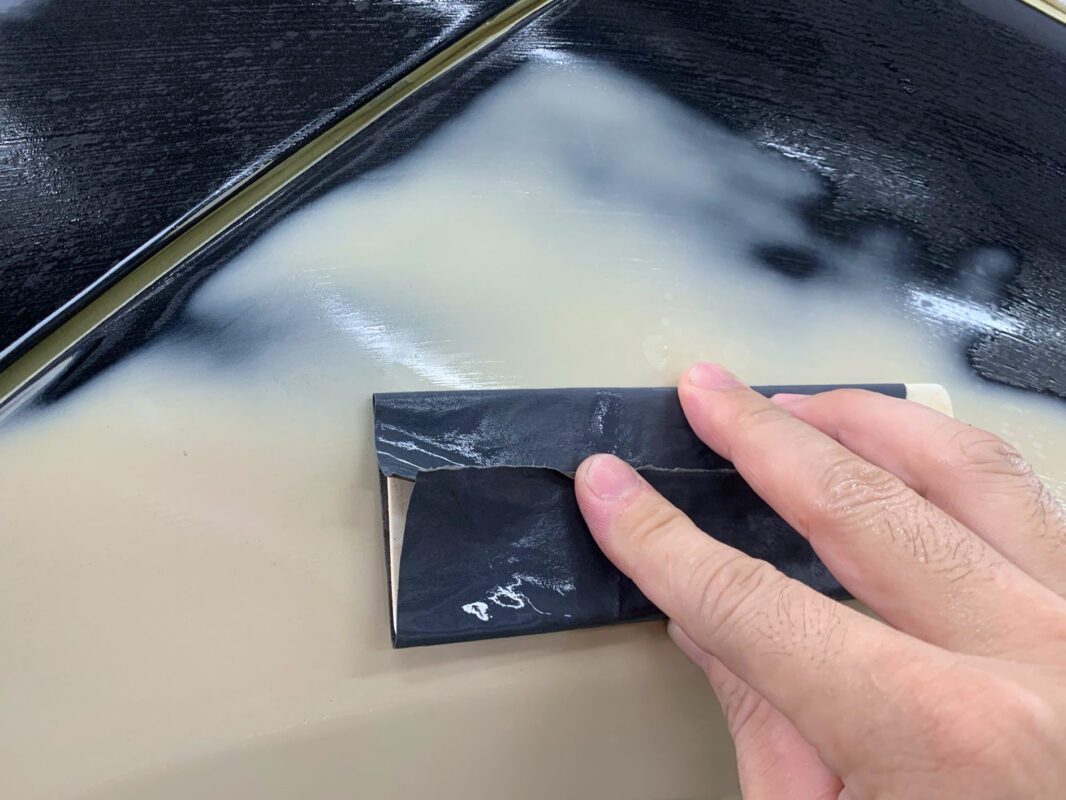 Continued surface preparation on Day 4, wet-sanding the BMW 520i smooth.