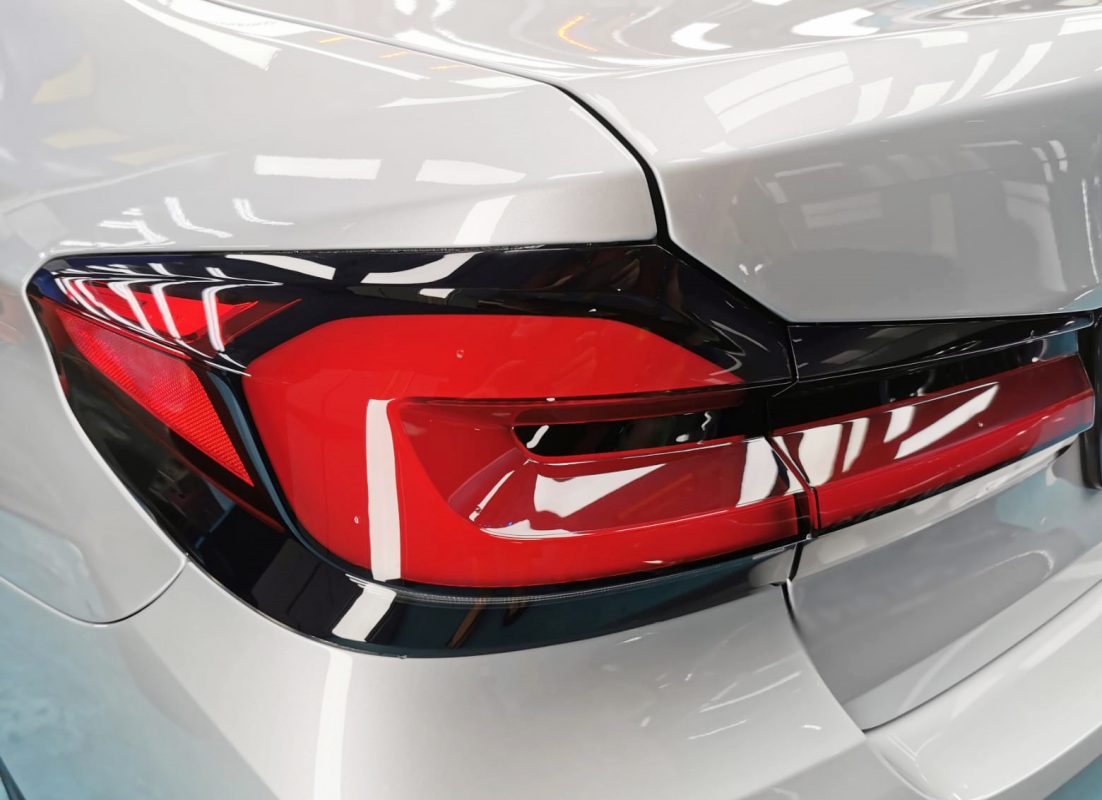 The coated bonnet of the BMW 520i under workshop lighting.