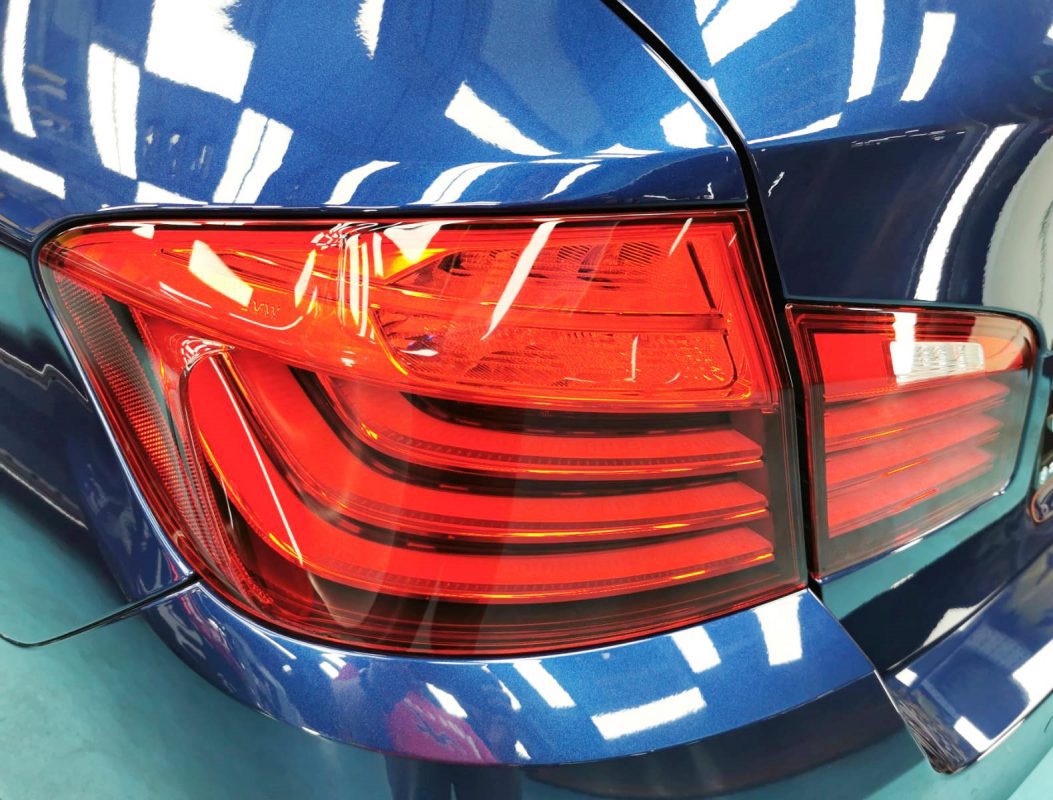 The coated bonnet of the BMW 520i under workshop lighting.