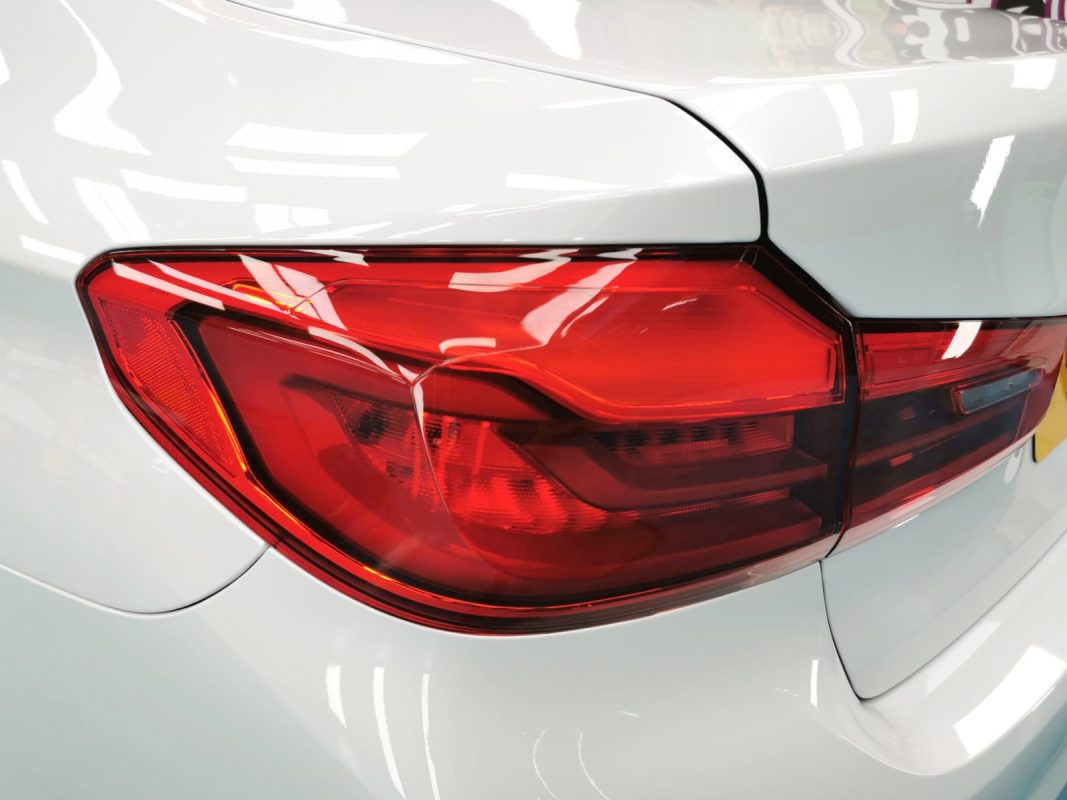 Coated bonnet of the BMW 520i under workshop lighting.