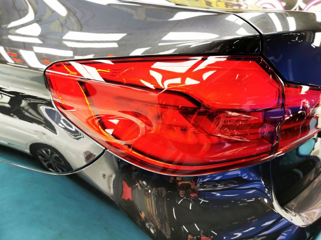 The coated bonnet of the BMW 520i under workshop lighting.