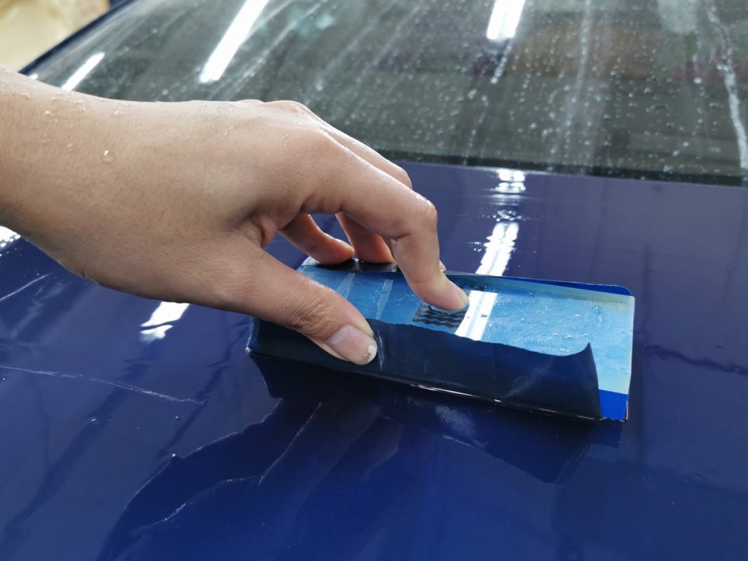 Wet-sanding the 523i's panels to smooth the surface.