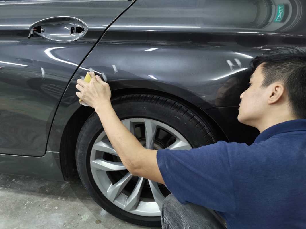 Revol Carz technician checking the BMW 528i's surface, patching imperfections before painting.