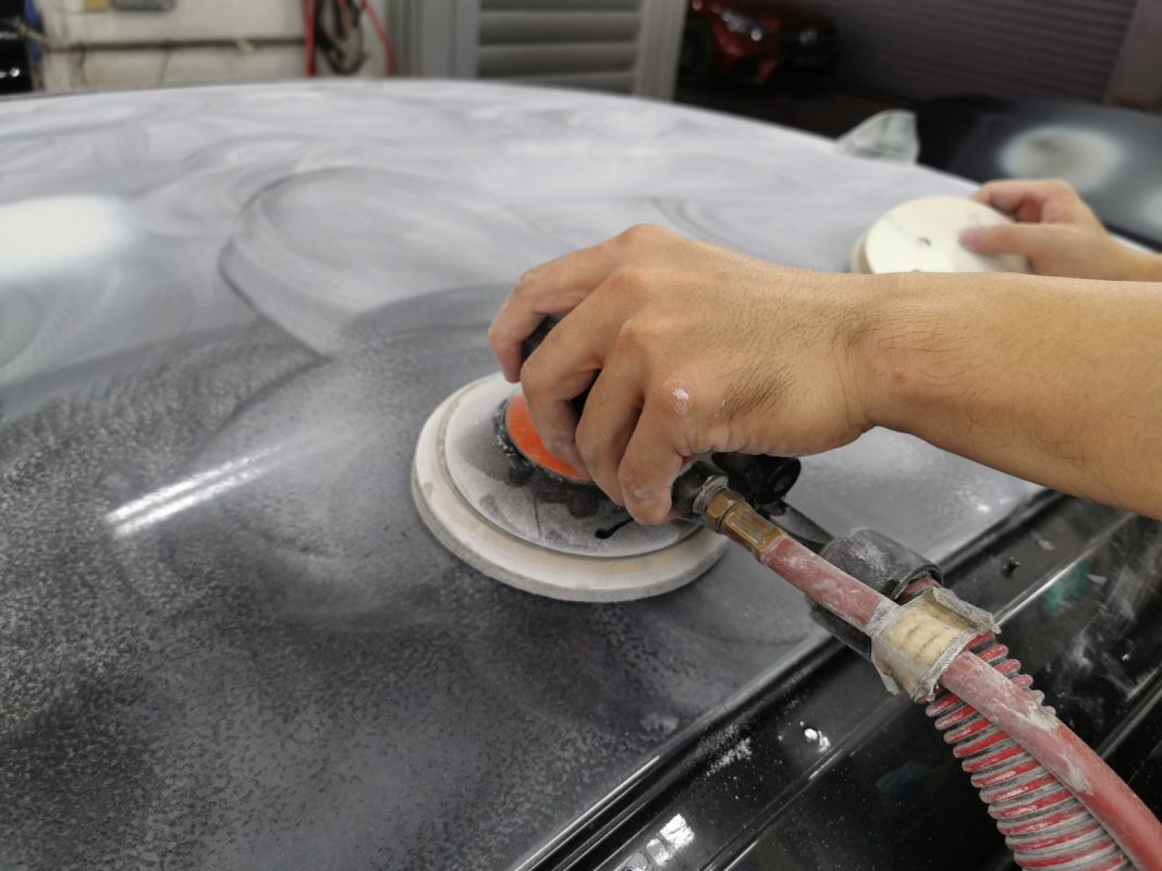 Sanding the BMW 528i's panel to bring the surface flat and even.