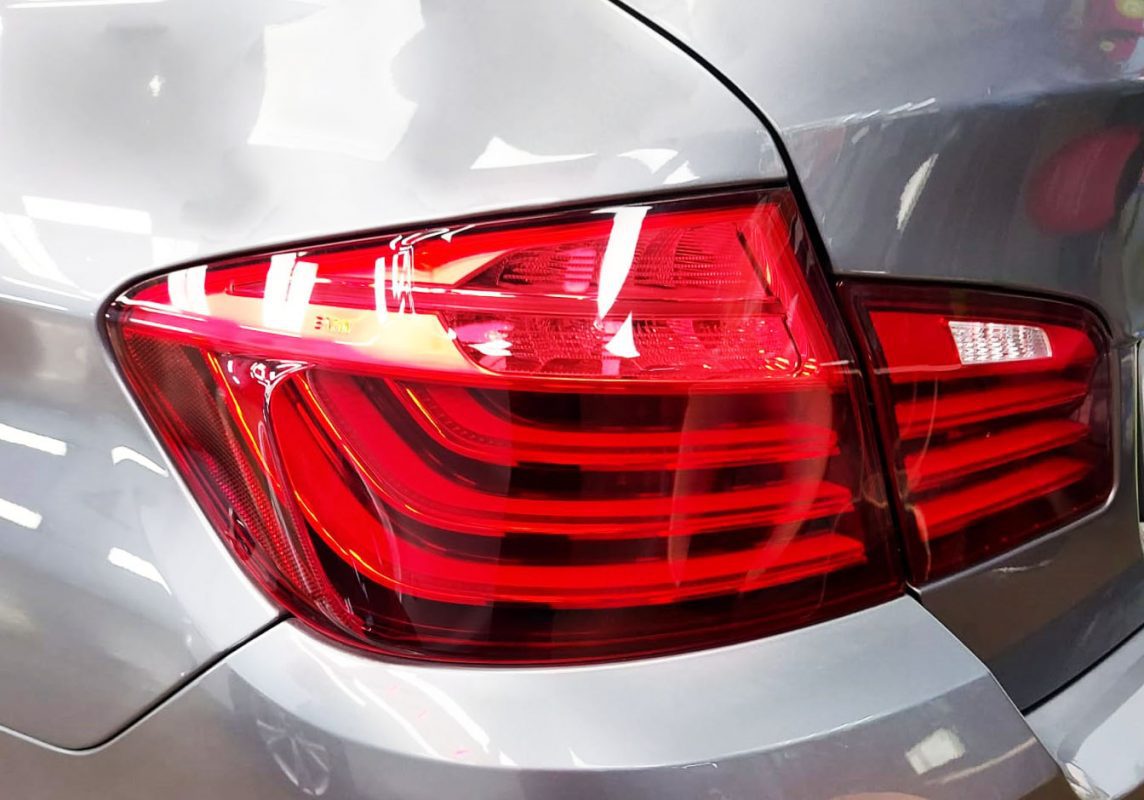 The coated bonnet of the BMW 528i under workshop lighting.