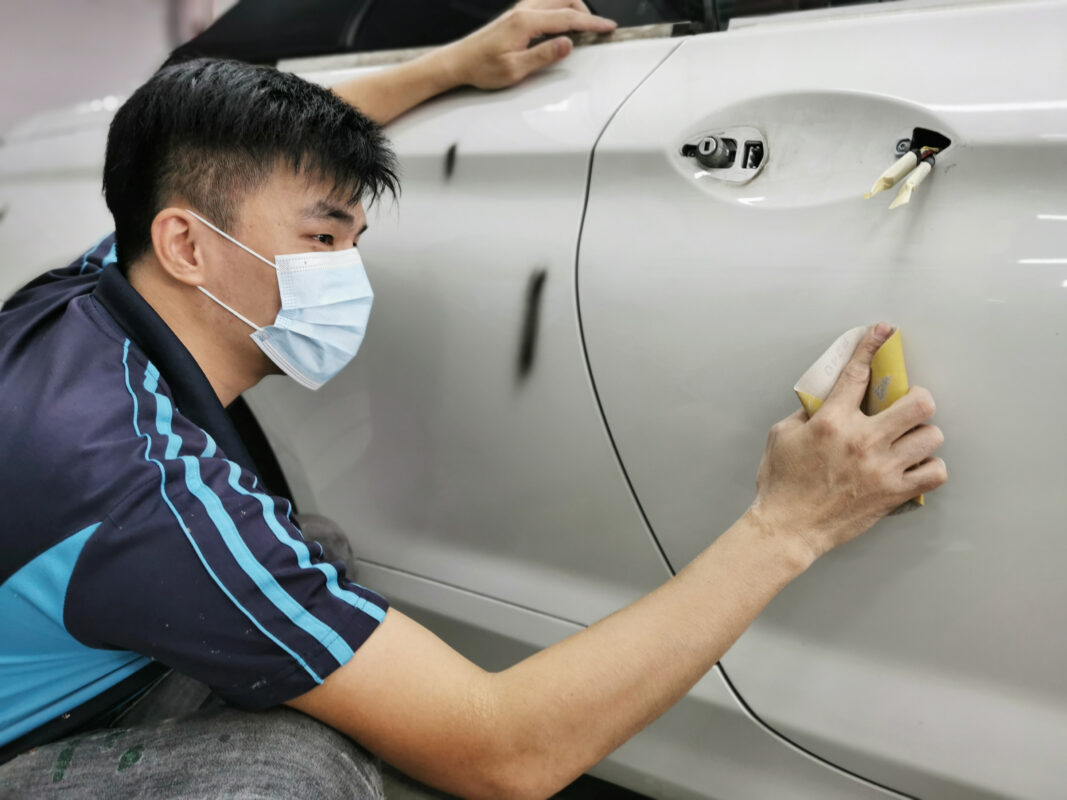 Body filler being applied and shaped on a panel of the BMW 6 Series.