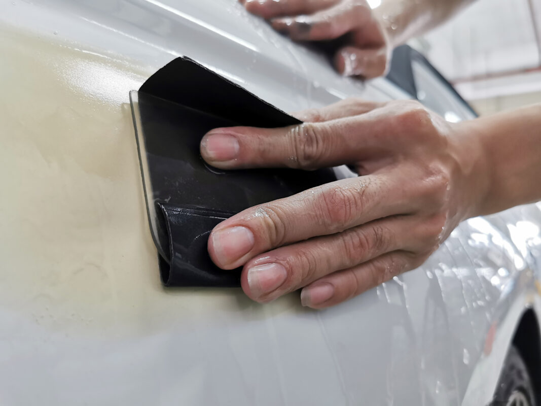 Wet-sanding a panel on the BMW 6 Series to level the surface before priming.