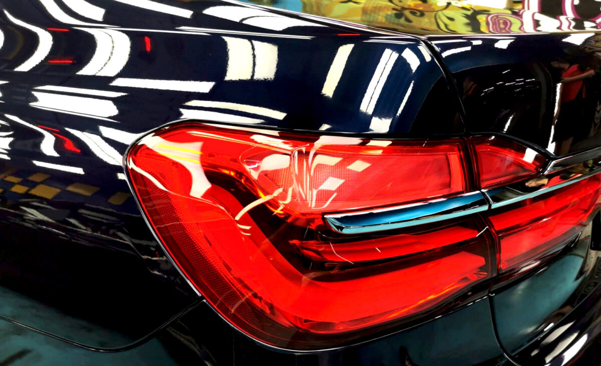 The coated bonnet of the BMW 7 Series under workshop lighting.
