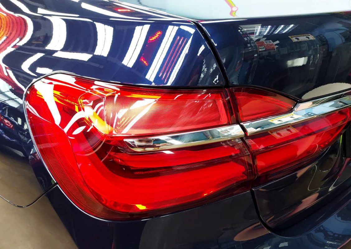 The coated bonnet of the BMW 740Li under workshop lighting.