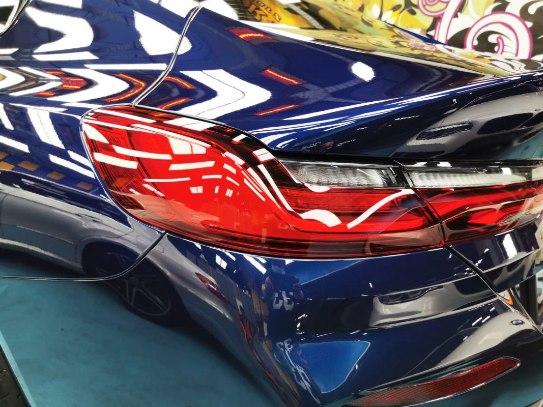 The coated bonnet of the BMW 8 Series under workshop lighting.