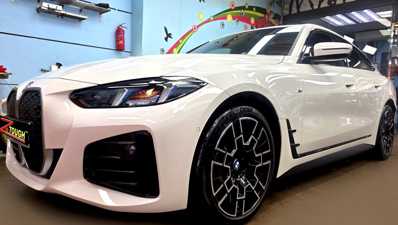 Front three-quarter view of a white BMW i4 in the workshop after coating.