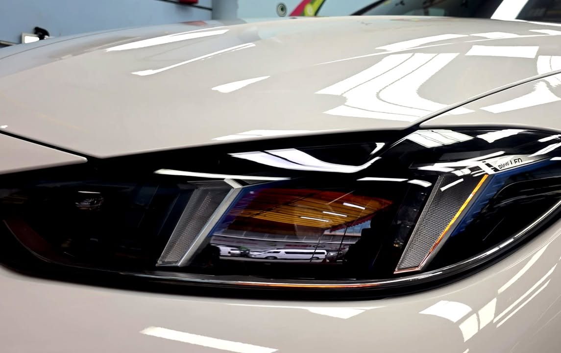 Close-up of the i4 headlight in white bodywork.