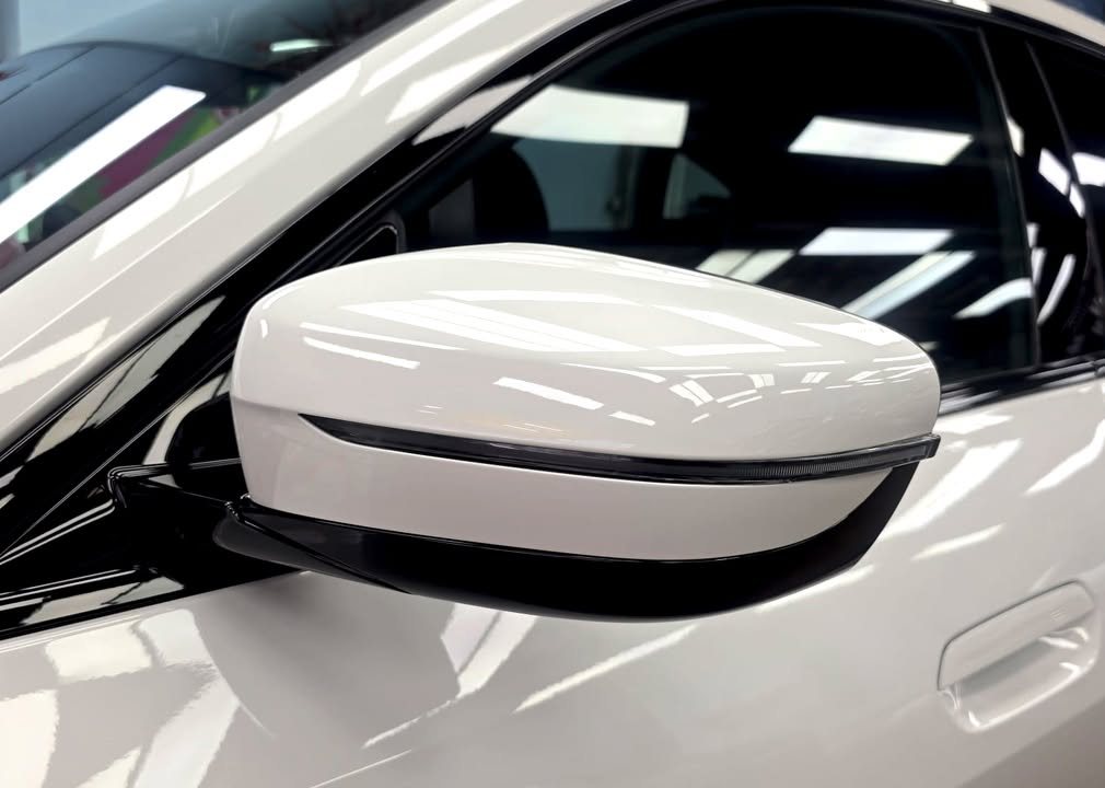 White side mirror cap on the i4 reflecting the ceiling lights.