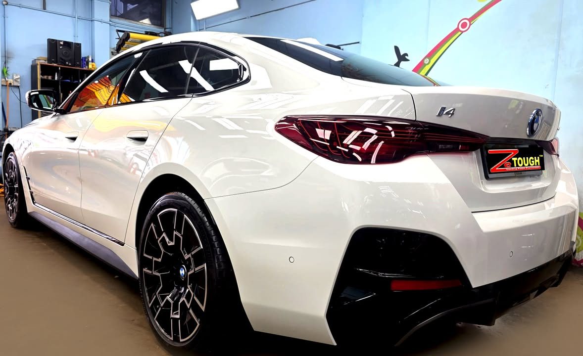 Rear three-quarter view of the white BMW i4 showing the tail lights and i4 badge.