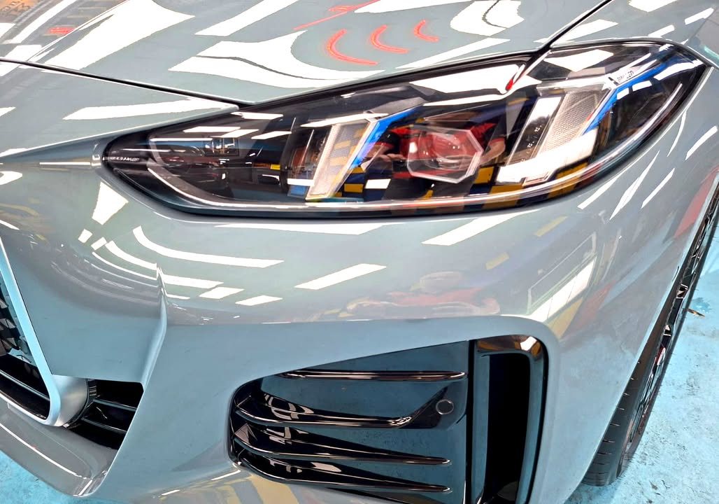 Close-up of the BMW i4 headlight and front air intake in grey paint.