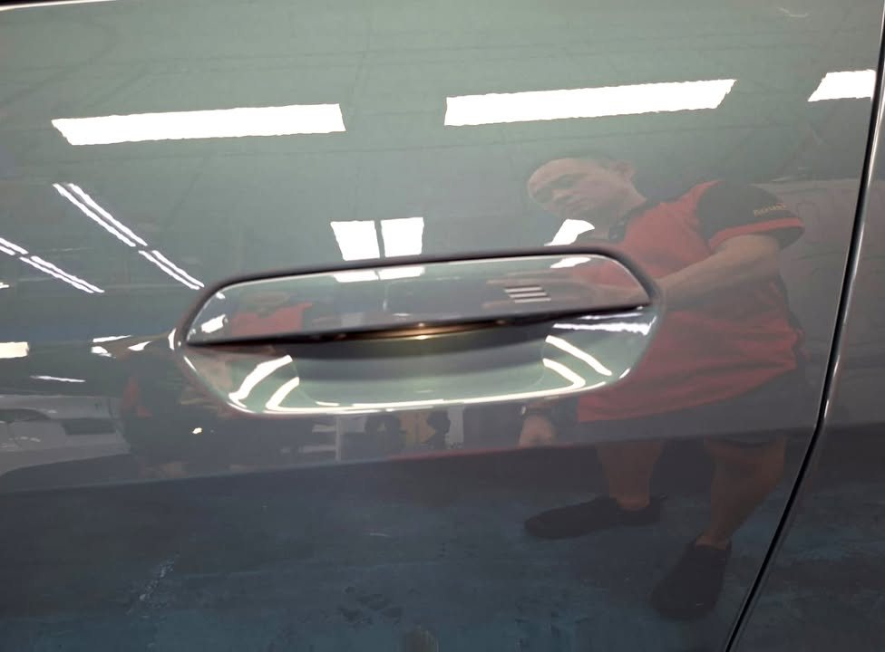 Grey door panel and door handle with a clear reflection in the paint.
