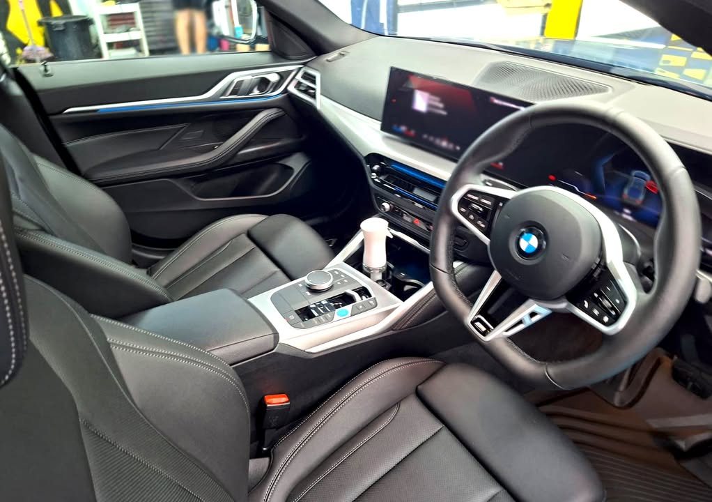 BMW i4 cabin with black leather seats, steering wheel and curved display.