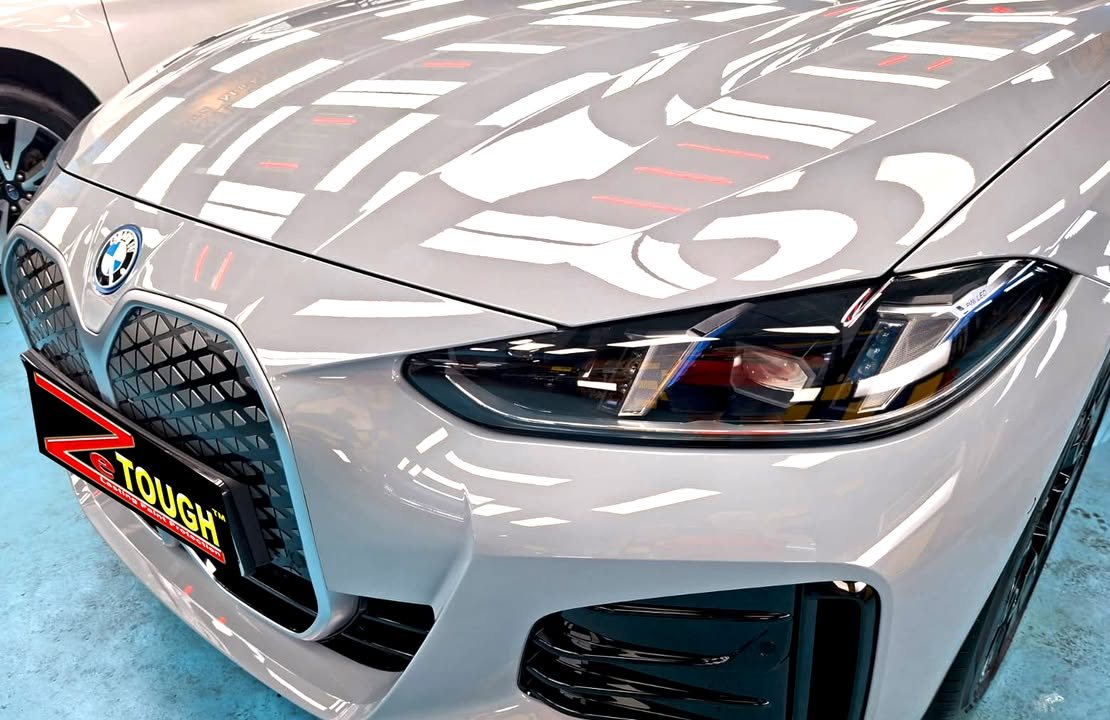 Close-up of the BMW i4 kidney grille and headlight, with studio lights reflected in the bonnet.