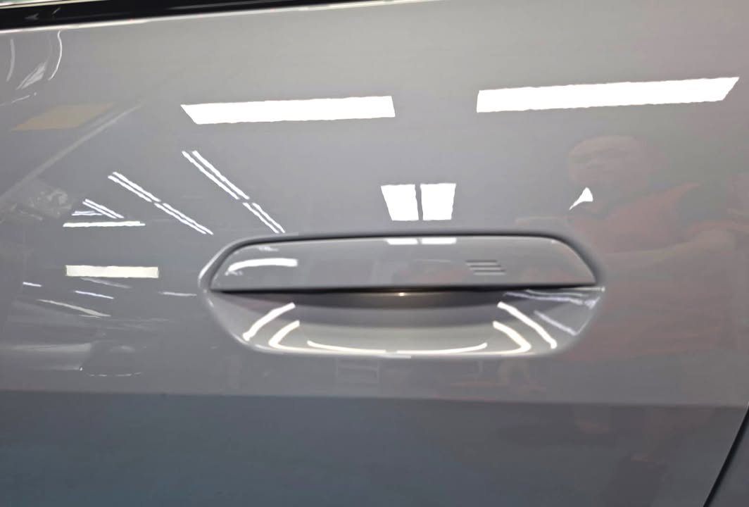 Close-up of the light grey door panel and flush door handle.