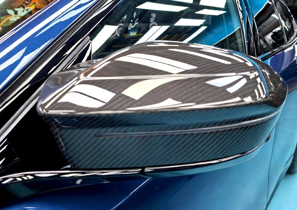 Close-up of the carbon fibre door mirror cap on the blue BMW i5.