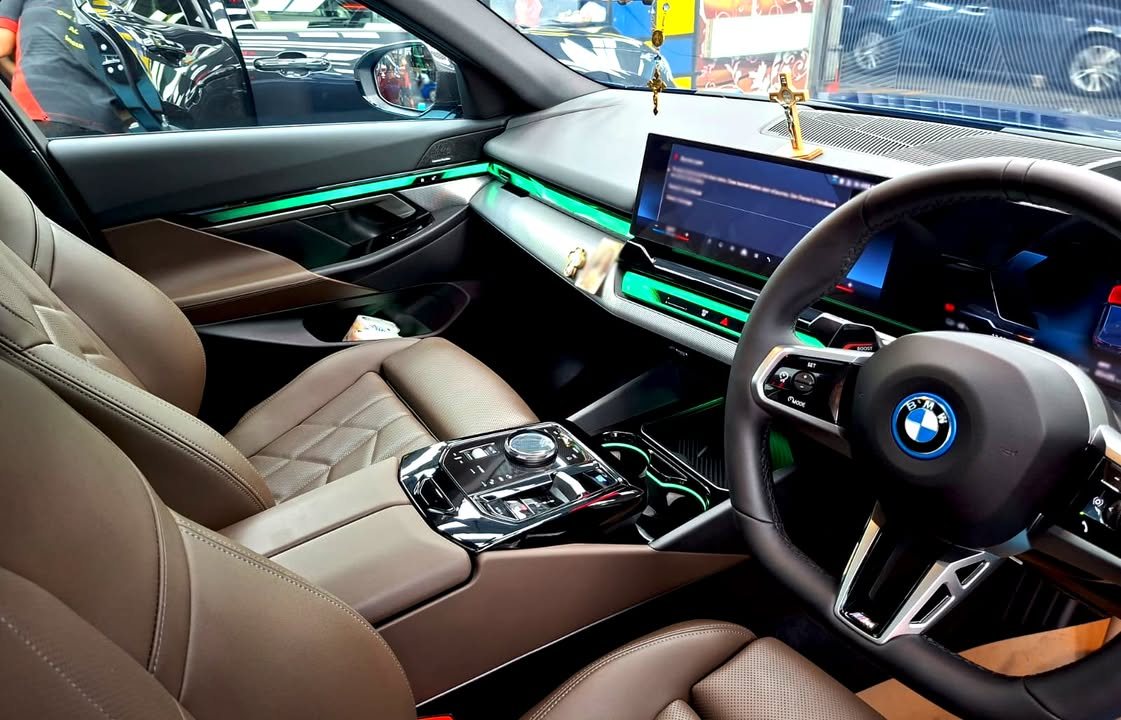 Interior of the BMW i5 with brown leather seats, steering wheel and curved display.