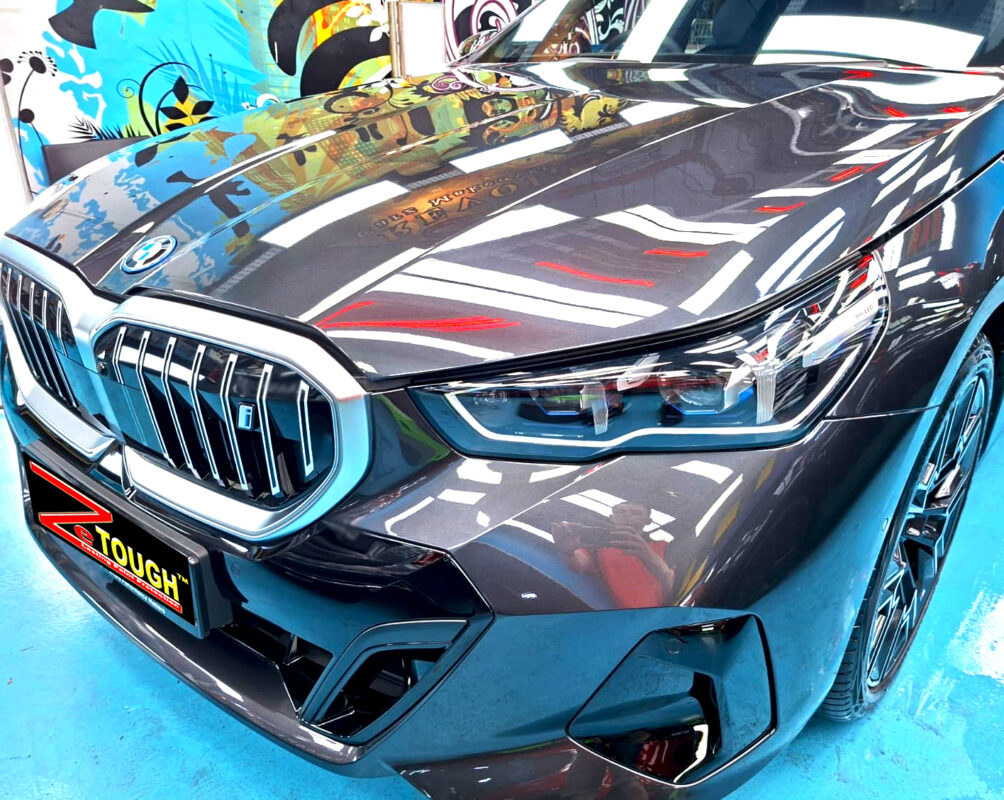 The BMW i5's coated paintwork under workshop lighting.