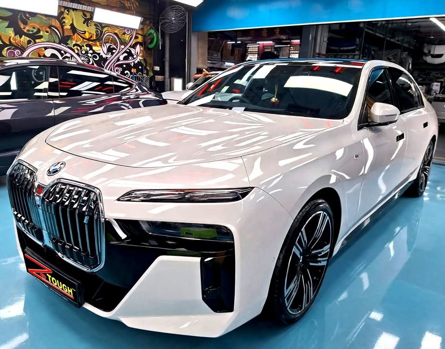 Front three-quarter view of a white BMW i7 with its large grille, parked in the Revol Carz hall after coating.