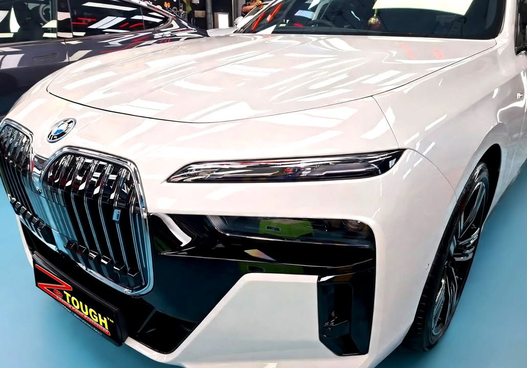 Front of the white BMW i7 showing the grille, slim headlight and bonnet shine.