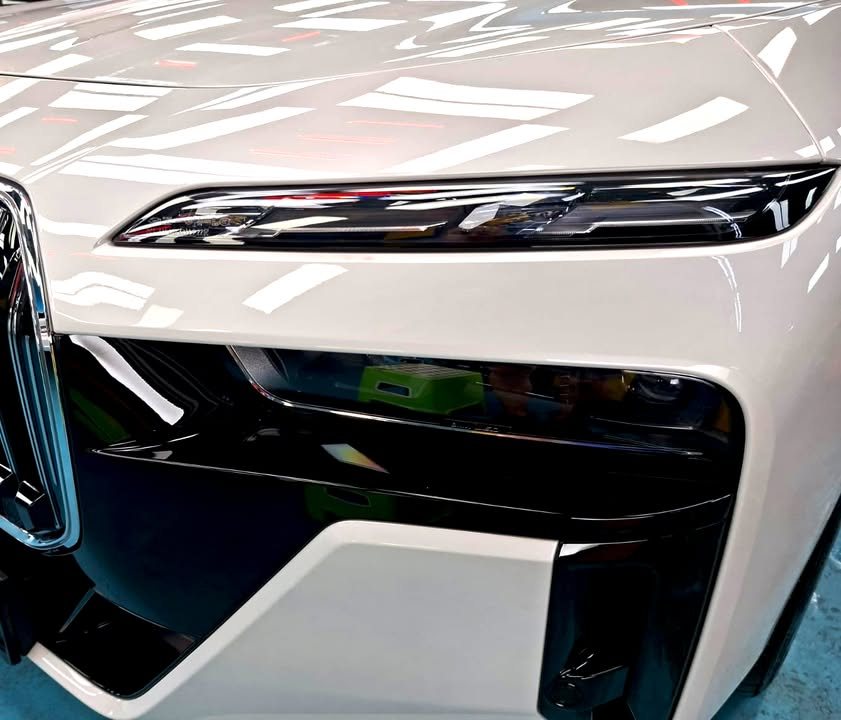Close-up of the i7's slim upper headlight and black lower lamp housing in white bodywork.