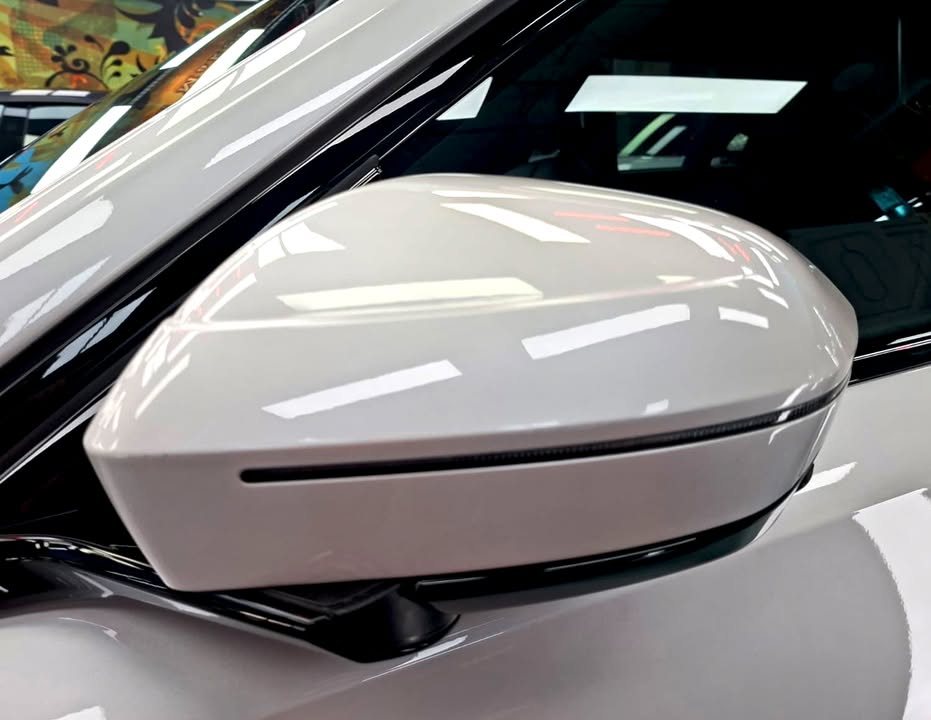 White side mirror cap on the BMW i7 reflecting the workshop lights.